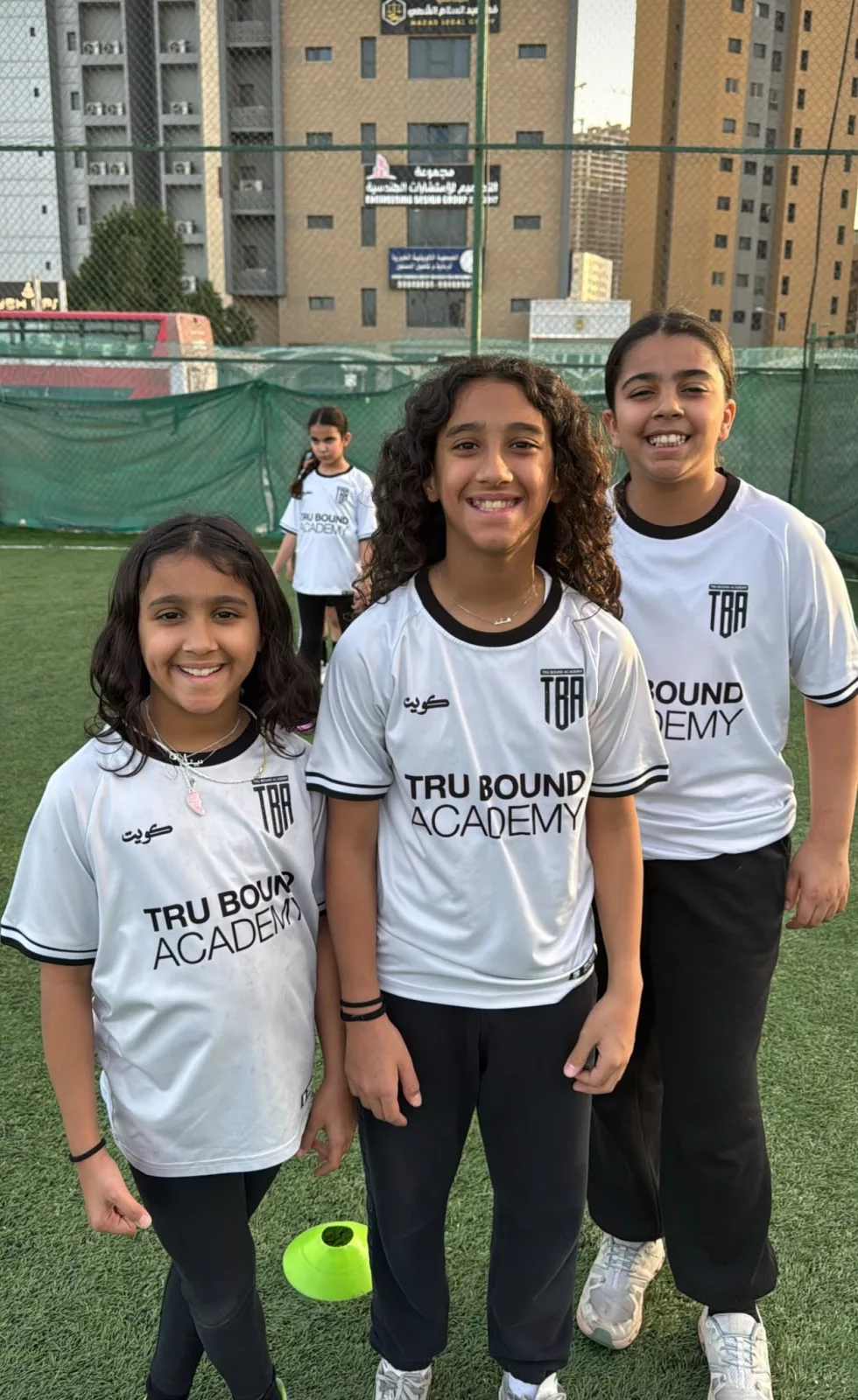 Three academy players smiling together after training